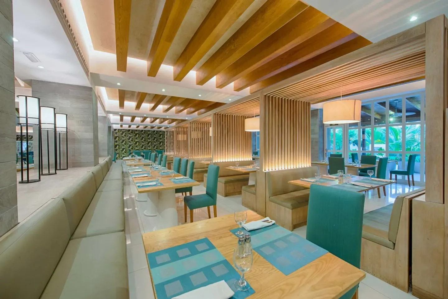Wood-accented dining room with teal chairs at Grand Sirenis Punta Cana Resort & Aquagames.