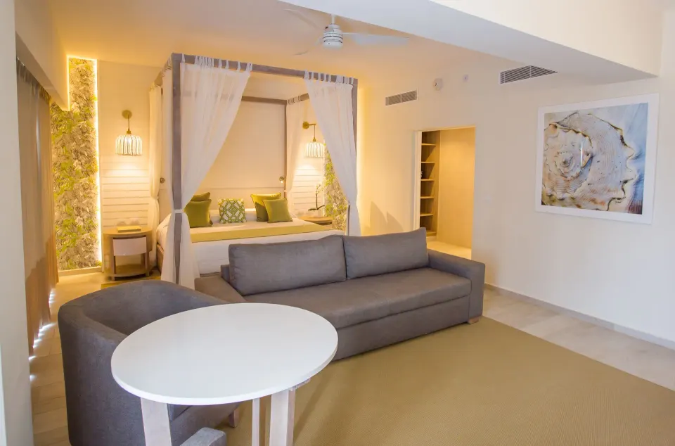 Renovated suite with sofa, round table and canopy bed at Grand Sirenis Punta Cana Resort & Aquagames.