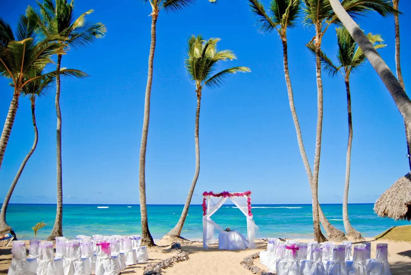 Beach wedding setup with white chairs and arch at Grand Sirenis Punta Cana Resort & Aquagames.