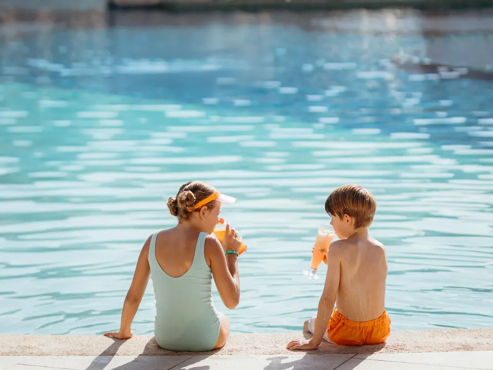 Two children sipping drinks at the pool edge at Grand Sirenis Riviera Maya Resort & Spa