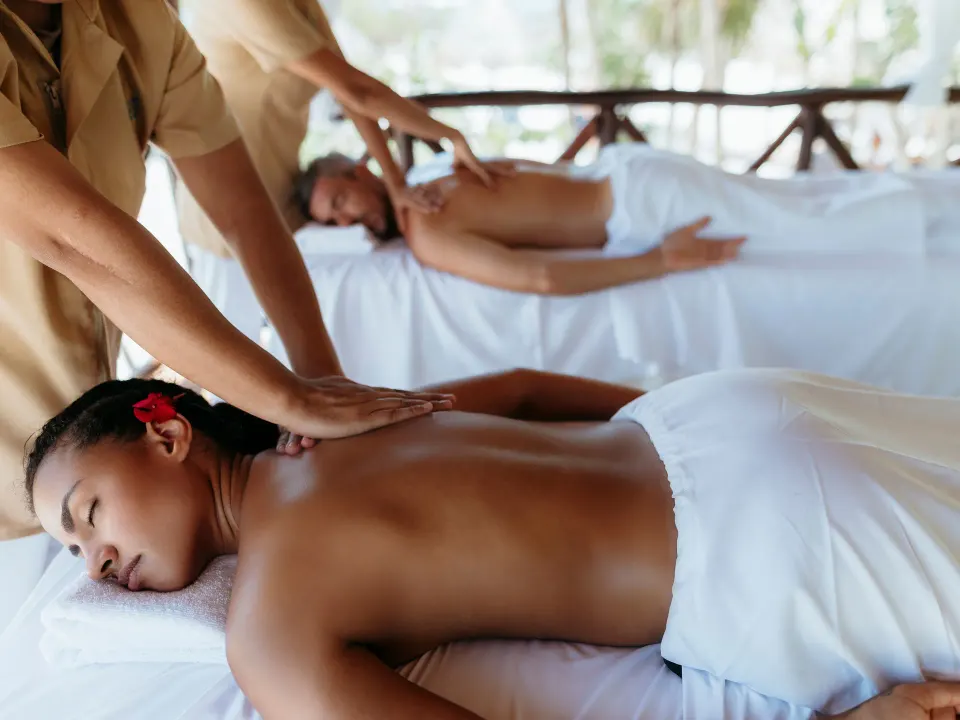 Two guests receiving back massages in an open spa treatment area at Grand Sirenis Riviera Maya Resort & Spa