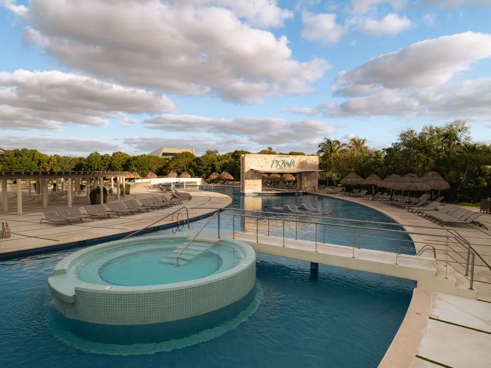 Circular hot tub and bridge with the Prana bar sign beyond at Grand Sirenis Riviera Maya Resort & Spa