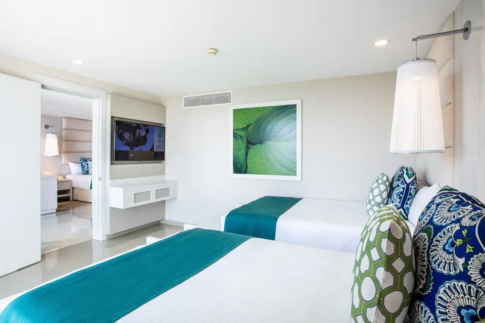 Interconnecting room view with two twin beds and green accents at Grand Sirenis Riviera Maya Resort & Spa