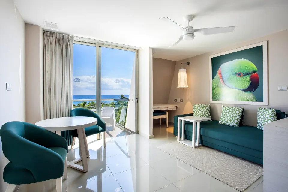 Junior suite seating area with sofa and ocean view balcony at Grand Sirenis Riviera Maya Resort & Spa