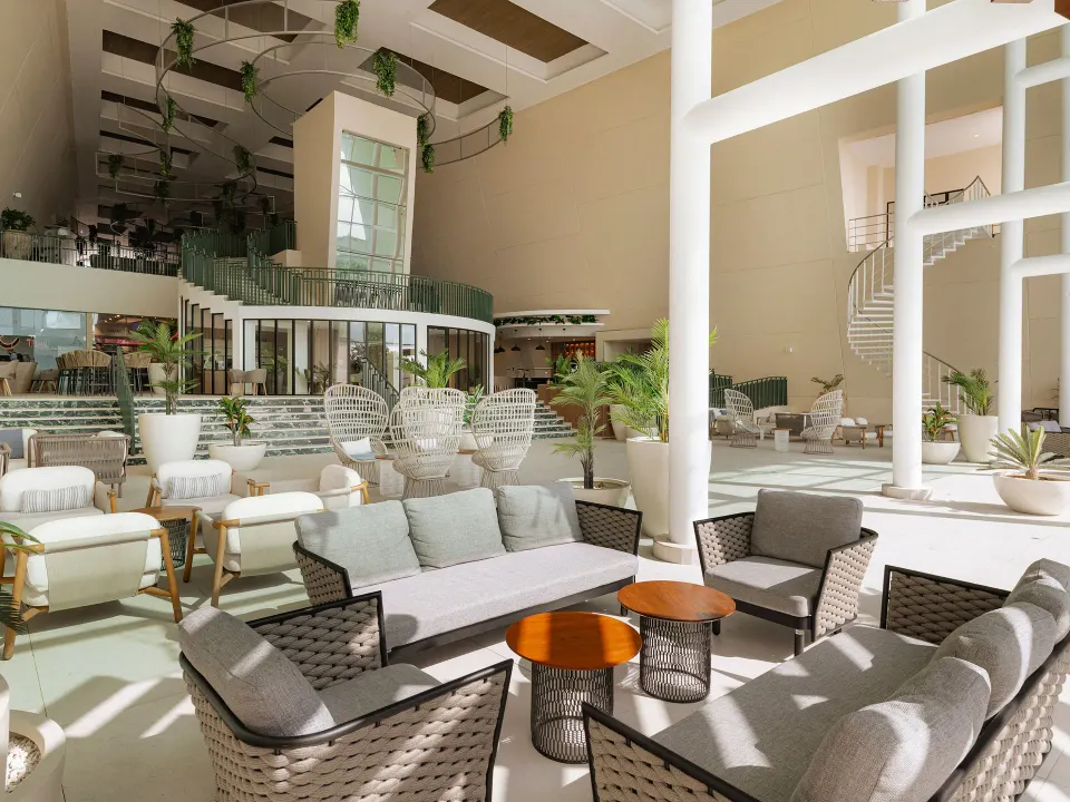 Lobby lounge sofas and coffee tables beneath a mezzanine at Grand Sirenis Riviera Maya Resort & Spa