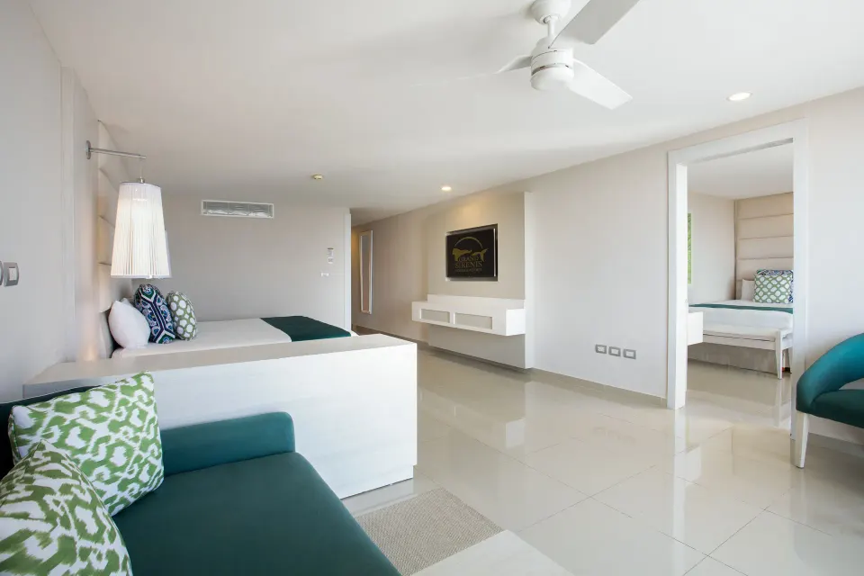 Spacious suite living area and bedroom with teal sofa at Grand Sirenis Riviera Maya Resort & Spa