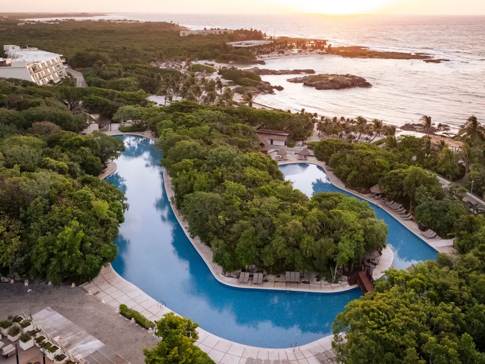 Sunset aerial of the resort's winding pools and coastline at Grand Sirenis Riviera Maya Resort & Spa