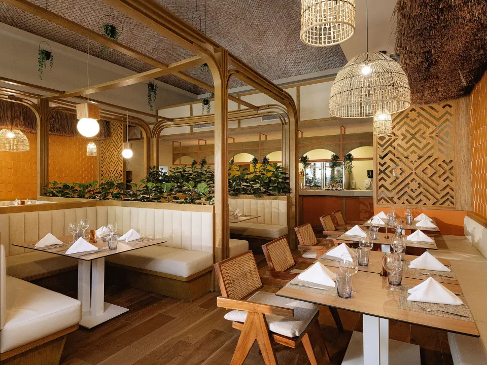 Warm booth seating and wicker lighting in a softly lit restaurant at Grand Sirenis Riviera Maya Resort & Spa