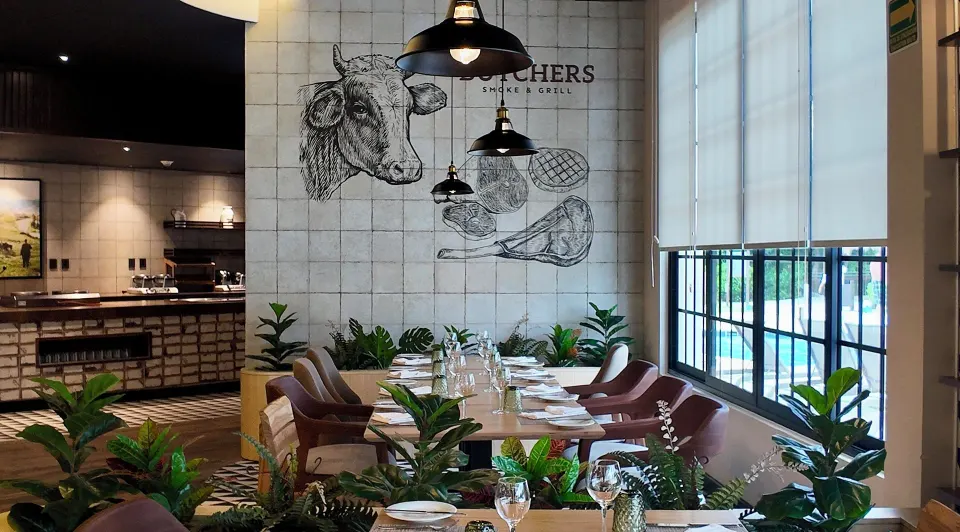 Dining area with butcher-themed wall art and tall windows at Grand Sirenis Riviera Maya Resort & Spa