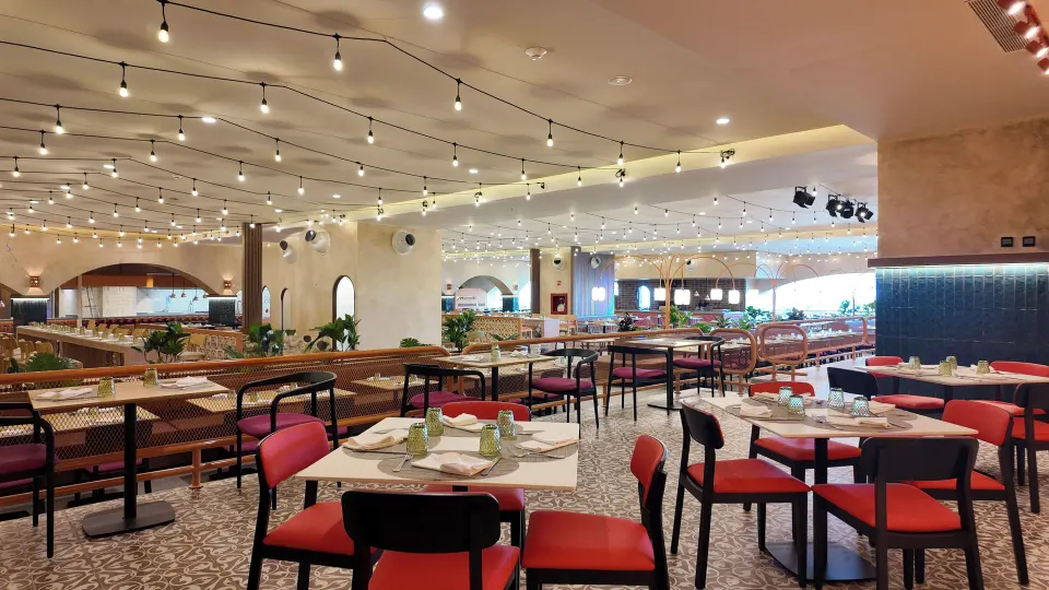 Large casual dining room with string lights and red-accent chairs at Grand Sirenis Riviera Maya Resort & Spa