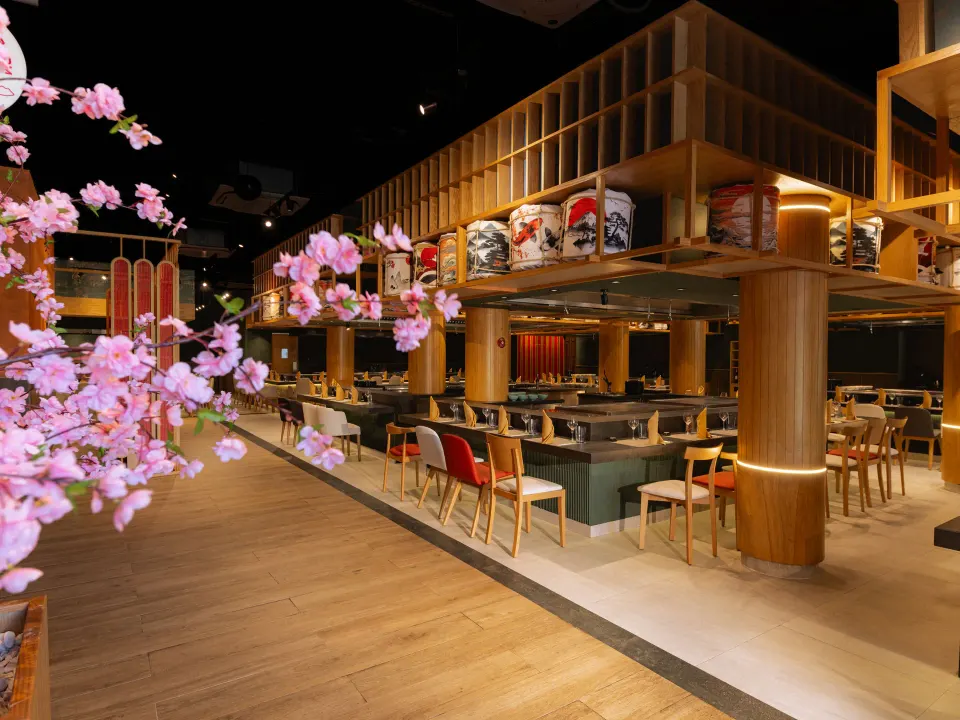 Spacious dining room with wooden booths and pink blossoms at Grand Sirenis Riviera Maya Resort & Spa