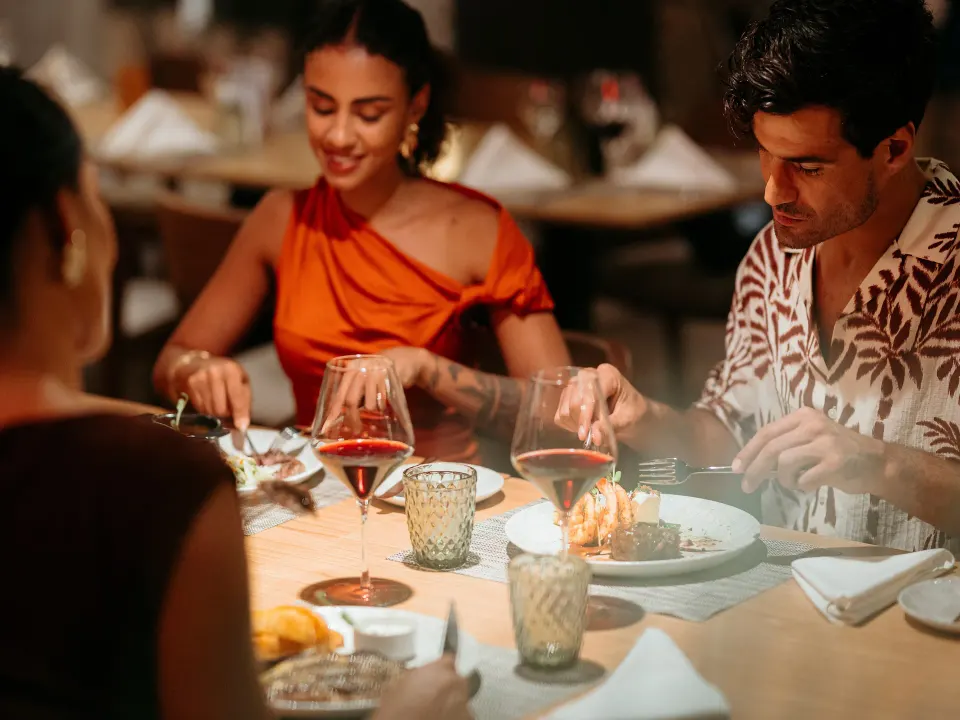 Couple dining with wine in a dimly lit restaurant at Grand Sirenis Riviera Maya Resort & Spa