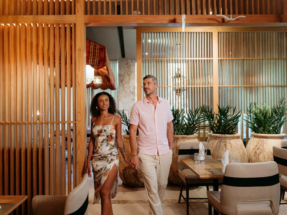 Couple walking through a wood-paneled dining room at Grand Sirenis Riviera Maya Resort & Spa
