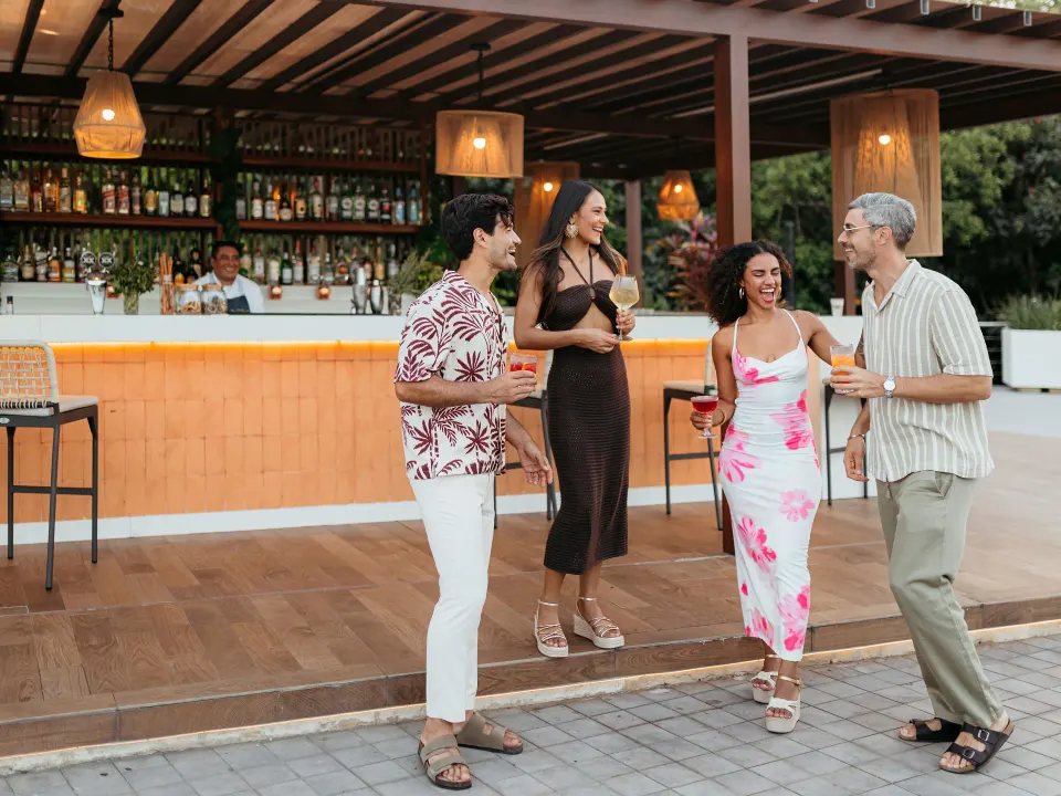 Guests chatting with drinks in front of an outdoor bar at Grand Sirenis Riviera Maya Resort & Spa