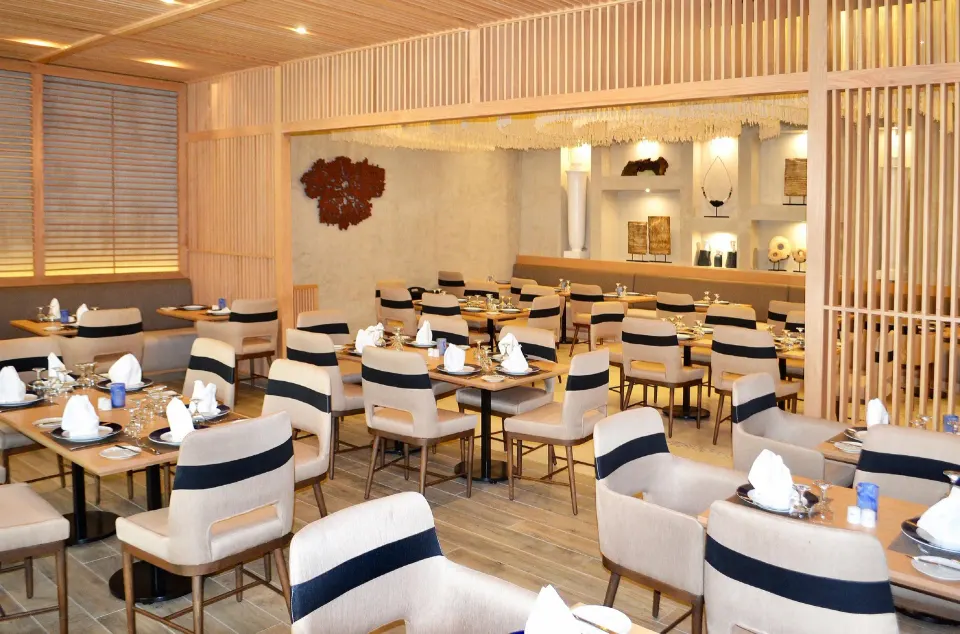 Light-wood dining room with coordinated chairs and place settings at Grand Sirenis Riviera Maya Resort & Spa