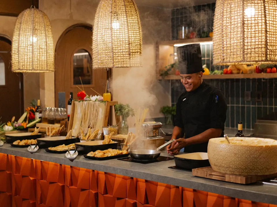 Chef cooking at a buffet pasta station under woven pendant lights at Grand Sirenis Riviera Maya Resort & Spa