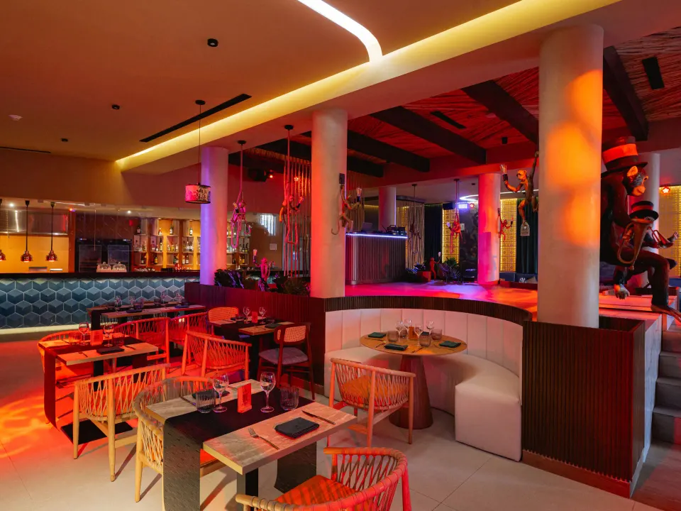 Dimly lit restaurant interior with stage and red accent lighting at Grand Sirenis Riviera Maya Resort & Spa
