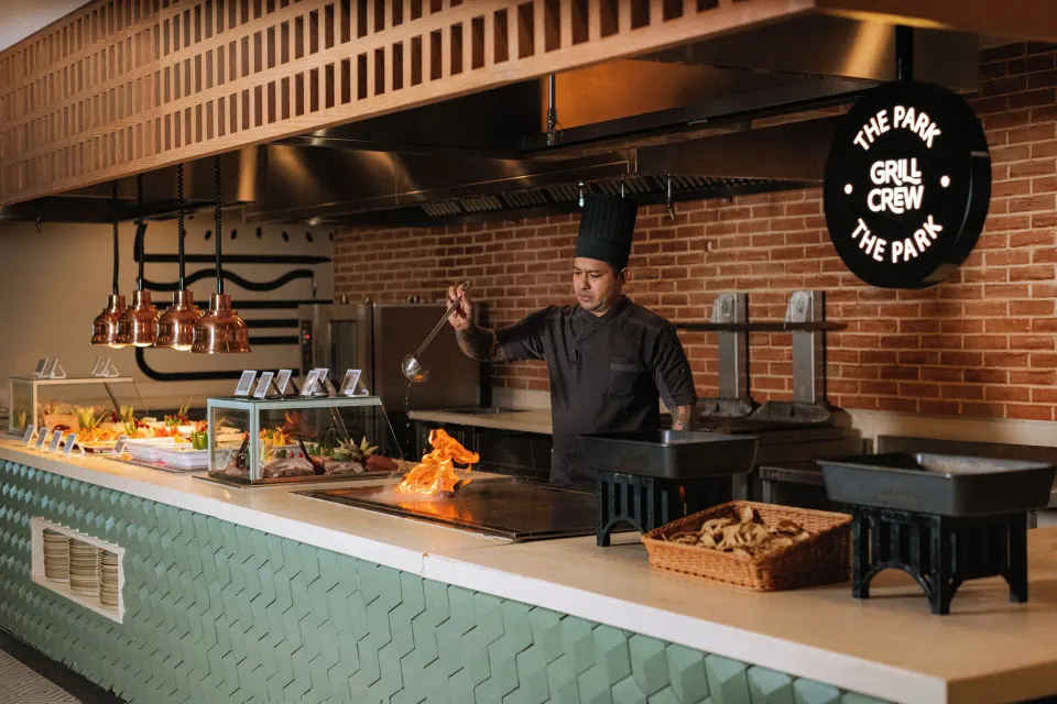 Chef cooking at an open grill counter in The Park at Grand Sirenis Riviera Maya Resort & Spa