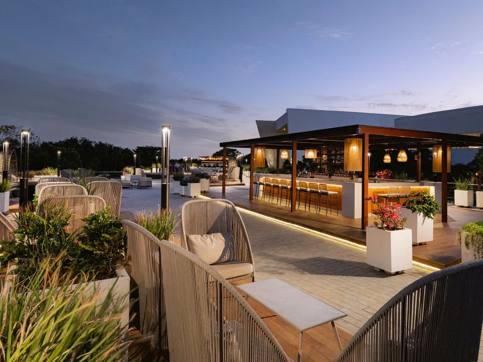 Evening rooftop bar with stools and woven lounge chairs at Grand Sirenis Riviera Maya Resort & Spa