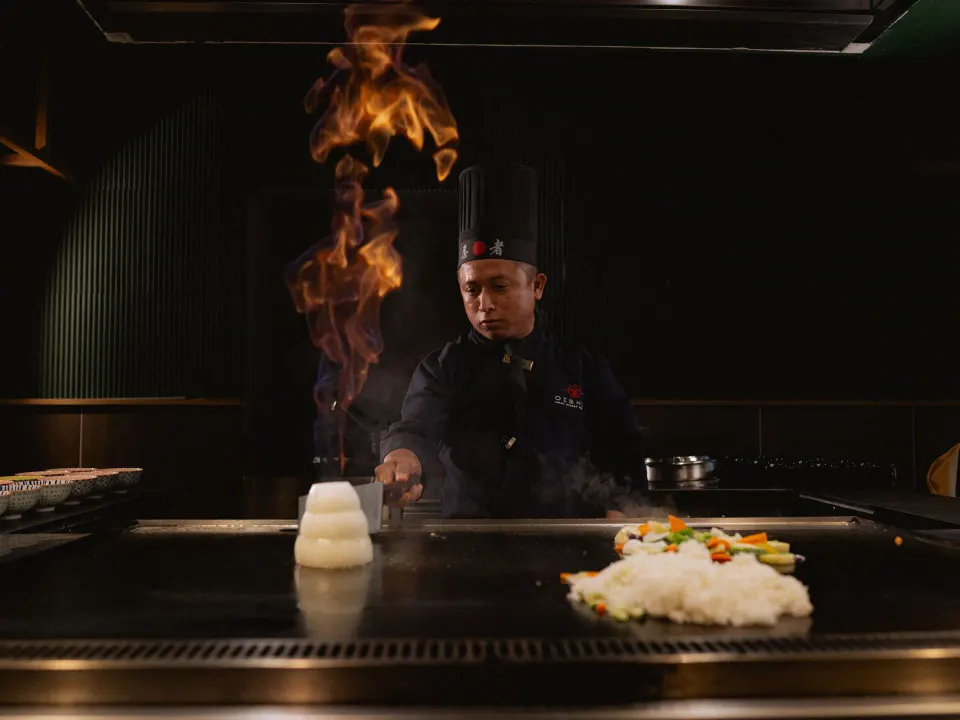Teppanyaki chef cooking on a flat grill with a flame at Grand Sirenis Riviera Maya Resort & Spa