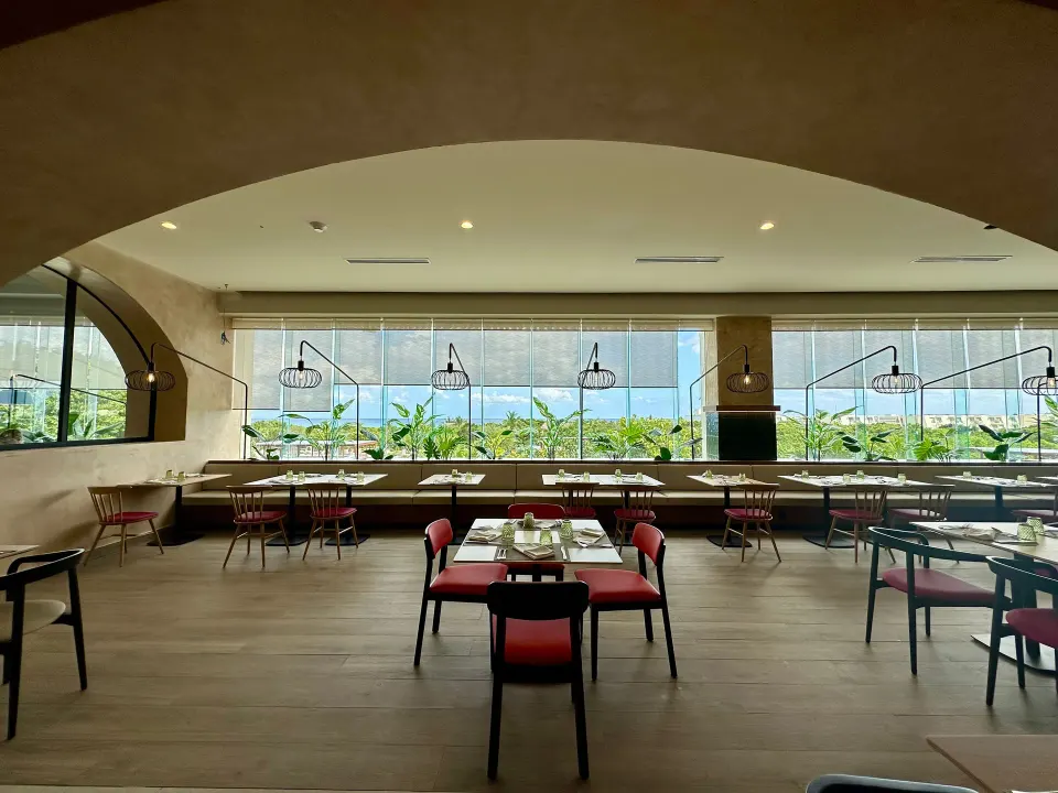 Wide-angle view of a window-lined dining room with pendant fixtures at Grand Sirenis Riviera Maya Resort & Spa