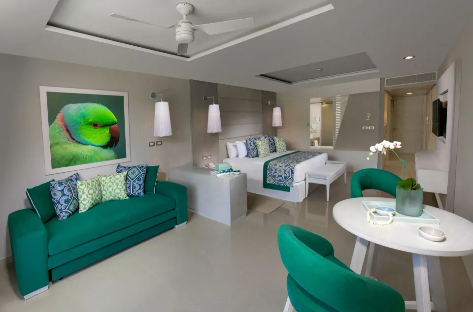 Junior suite with green sofa and king bed at Grand Sirenis Riviera Maya Resort & Spa