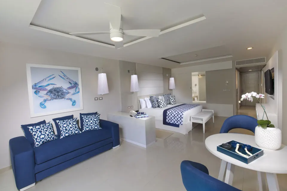 Junior suite with navy sofa, round table and king bed at Grand Sirenis Riviera Maya Resort & Spa