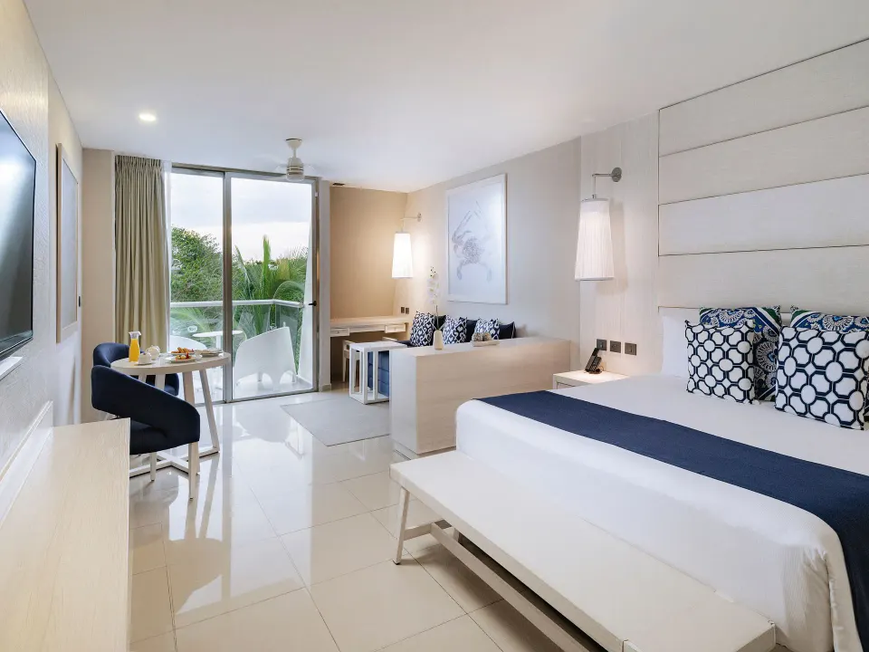 Junior suite with king bed, sofa and balcony at Grand Sirenis Riviera Maya Resort & Spa