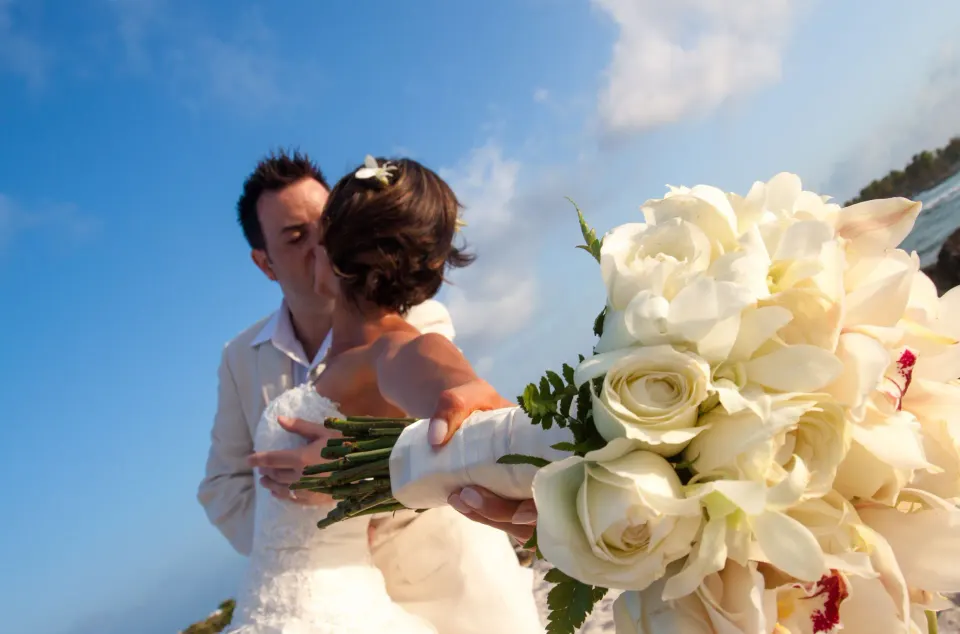 Bride and groom kissing with bouquet close-up at Grand Sirenis Riviera Maya Resort & Spa