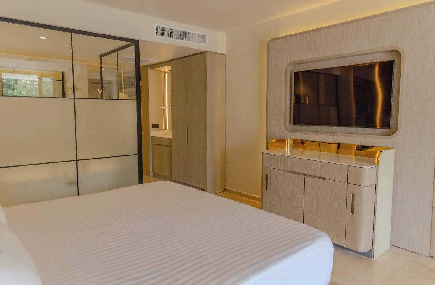 Guest room with king bed, wall-mounted TV and glass partition at Grand Sunset Princess.