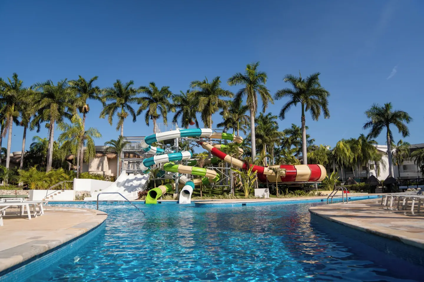 Pool with colorful water slides and palm trees at Grand Sunset Princess.