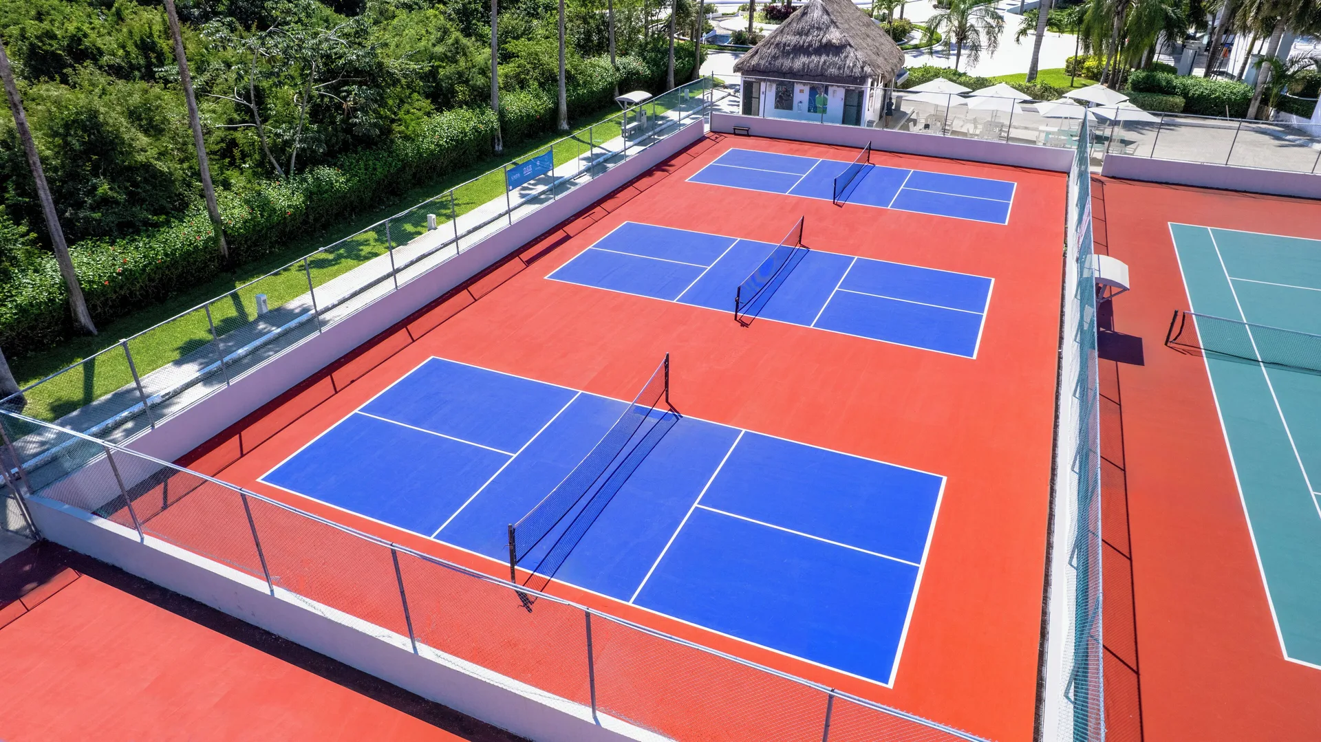 Blue-and-red racket sport courts at Grand Sunset Princess viewed from above.