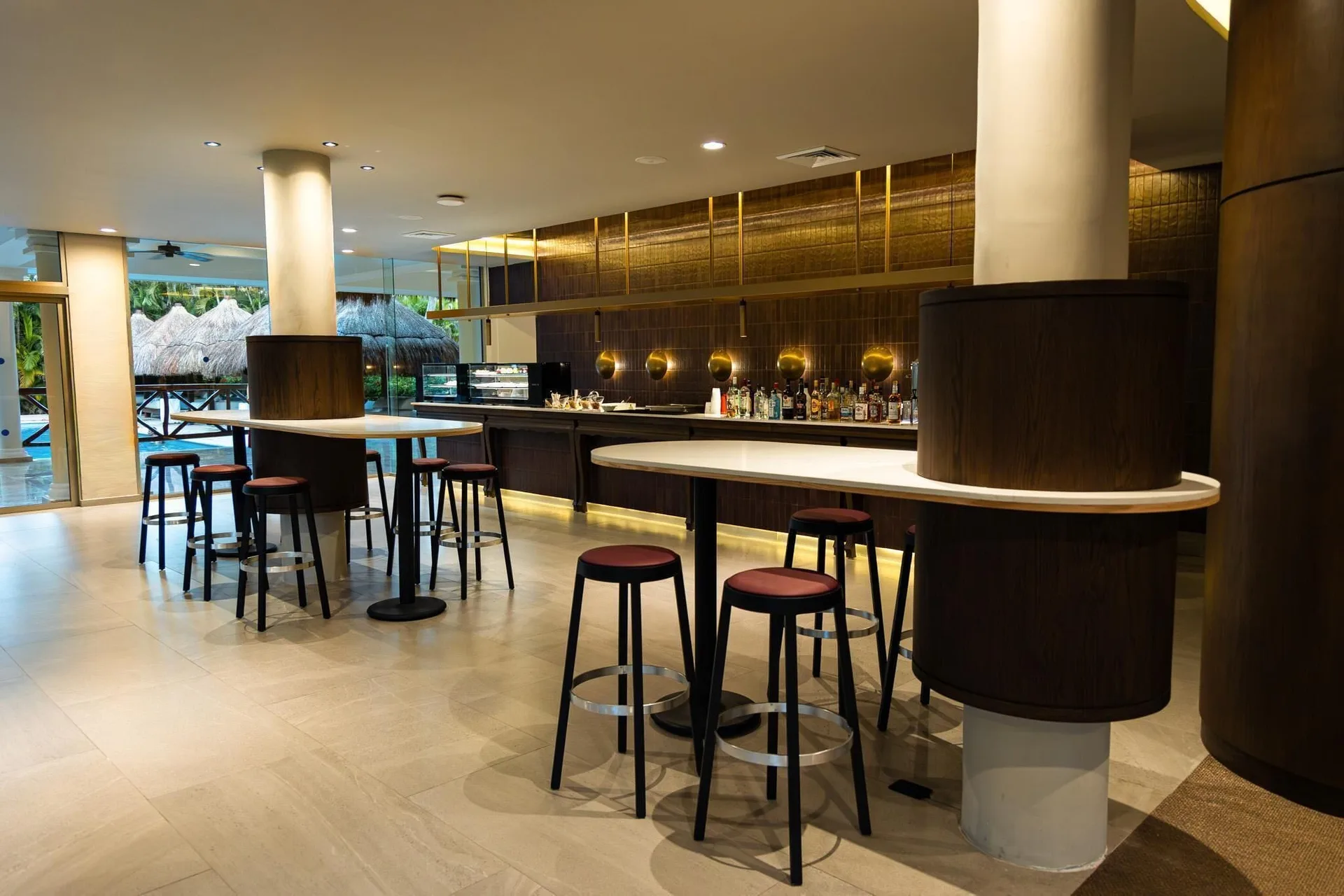 Indoor bar with high tables, stools and a poolside view at Grand Sunset Princess.