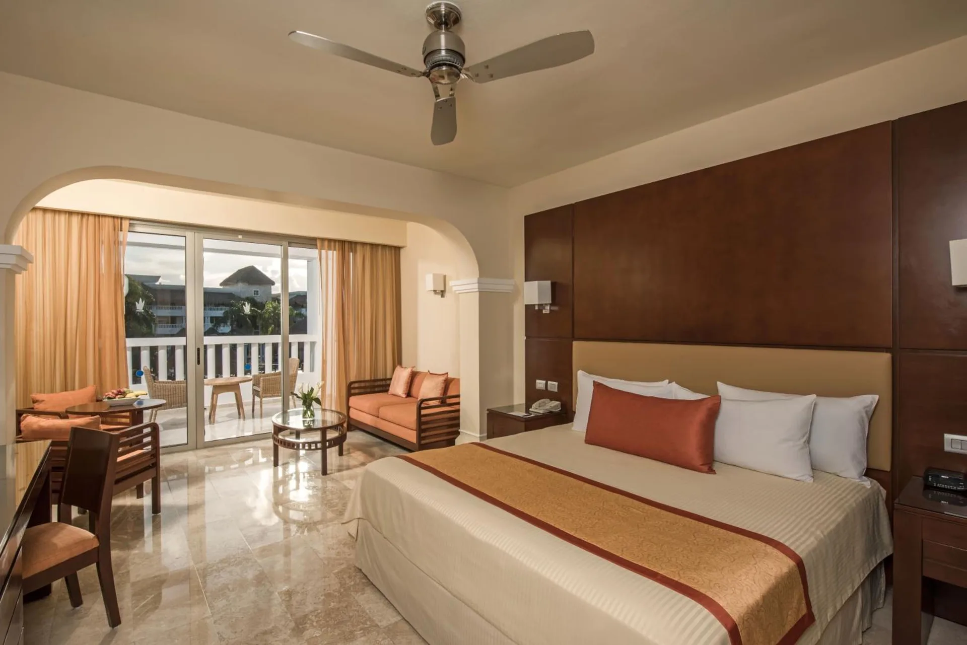 Deluxe Junior Suite with king bed, ceiling fan, sofa seating and balcony at Grand Sunset Princess.