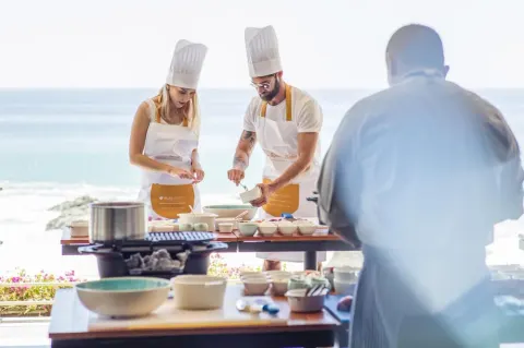 Cooking class by the ocean at Grand Velas Los Cabos with guests and a chef at prep tables.