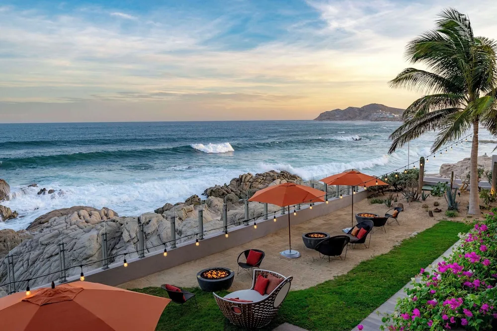 Oceanfront garden lounge with umbrellas and fire bowls at Grand Velas Los Cabos.