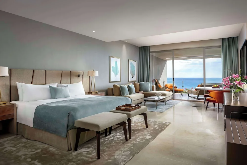 Ambassador Suite Ocean View king bed, lounge seating, and balcony at Grand Velas Los Cabos.