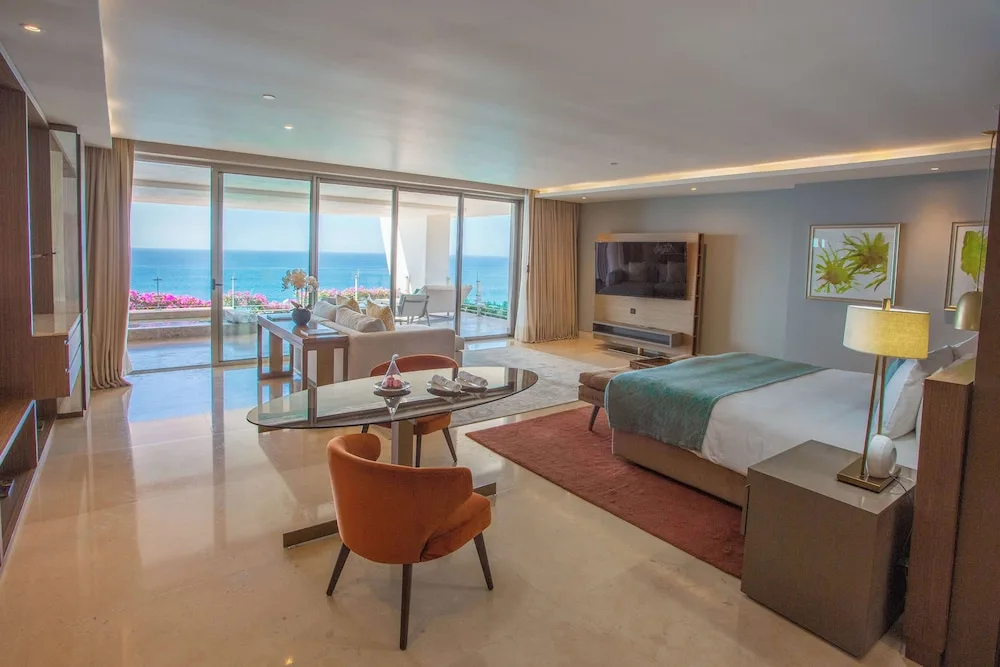 Grand Class Corner Suite with king bed, dining table, sofa, terrace, and ocean view at Grand Velas Los Cabos.
