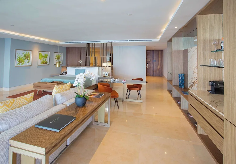 Grand Class Corner Suite with king bed, sofa, dining table and built-in bar at Grand Velas Los Cabos.