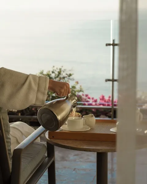 Tea being poured on a Grand Class Corner Suite terrace at Grand Velas Los Cabos with the ocean beyond.