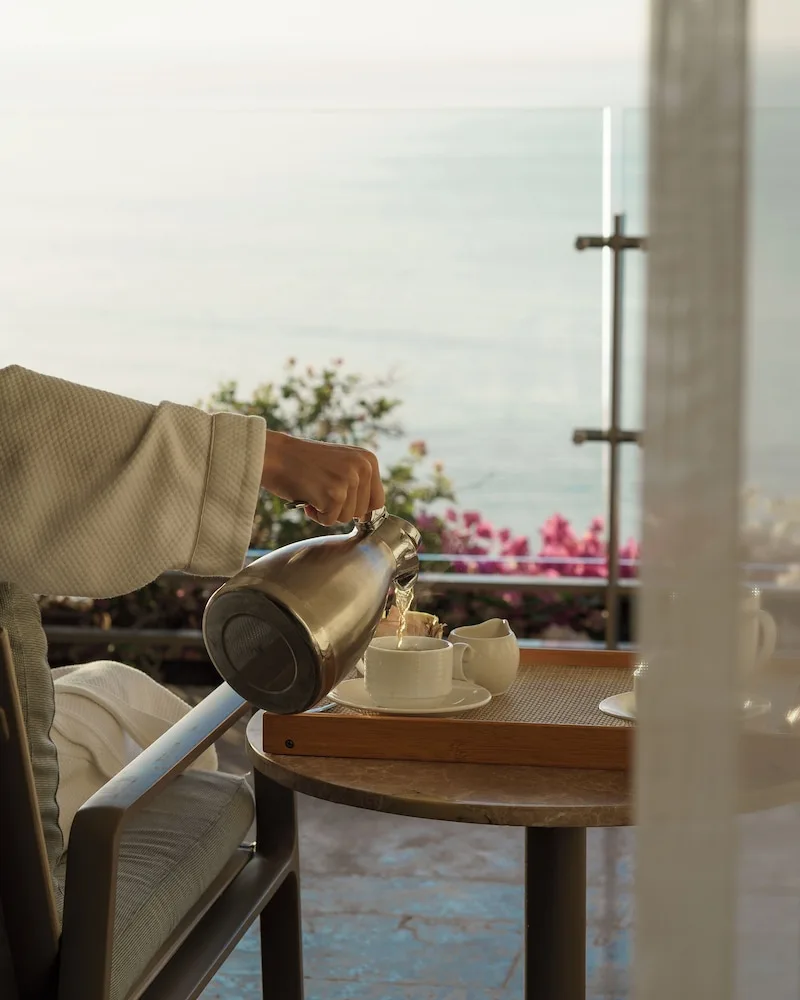 Tea being poured on a Grand Class Corner Suite terrace at Grand Velas Los Cabos with the ocean beyond.