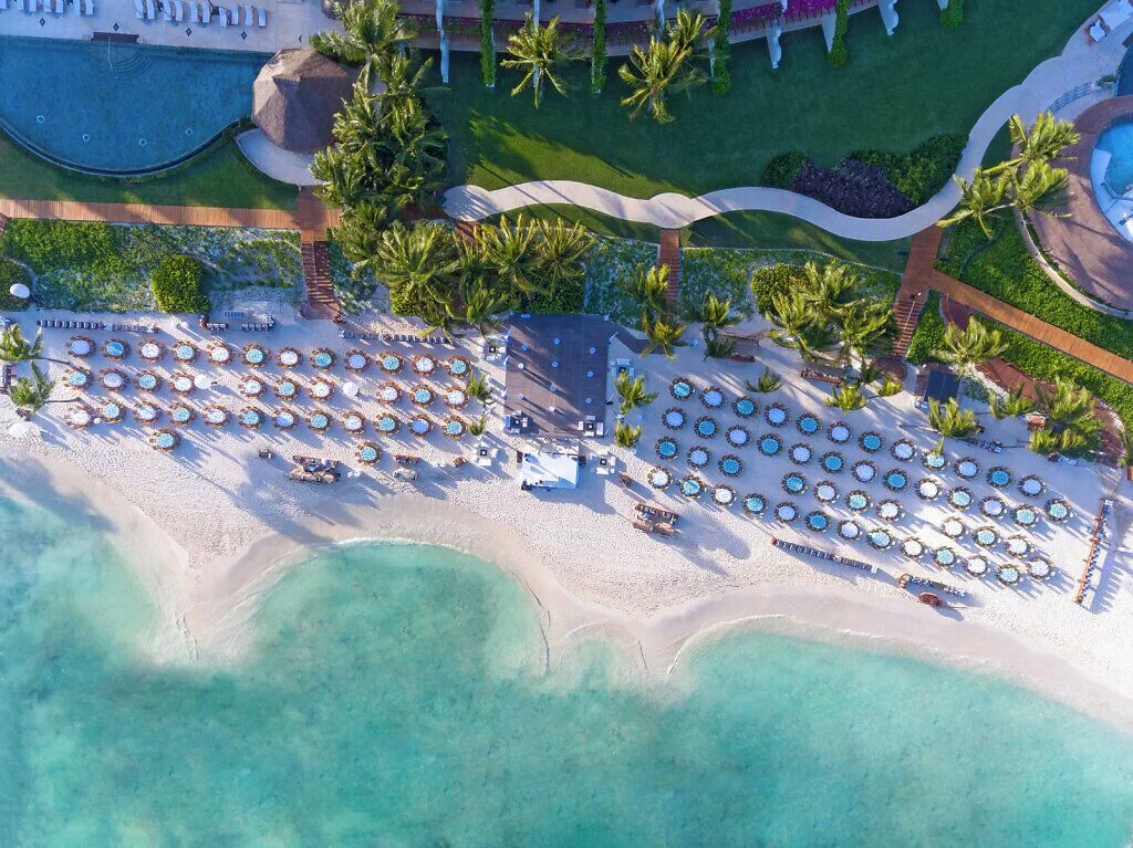 Aerial view of the beach, umbrellas, palms, and pools at Grand Velas Riviera Maya.