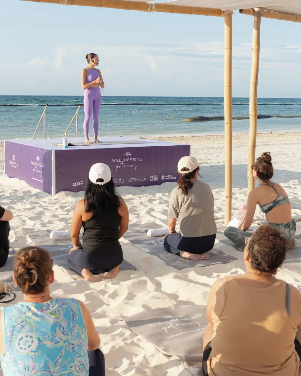 Beach wellness class faces an instructor by the sea at Grand Velas Riviera Maya.