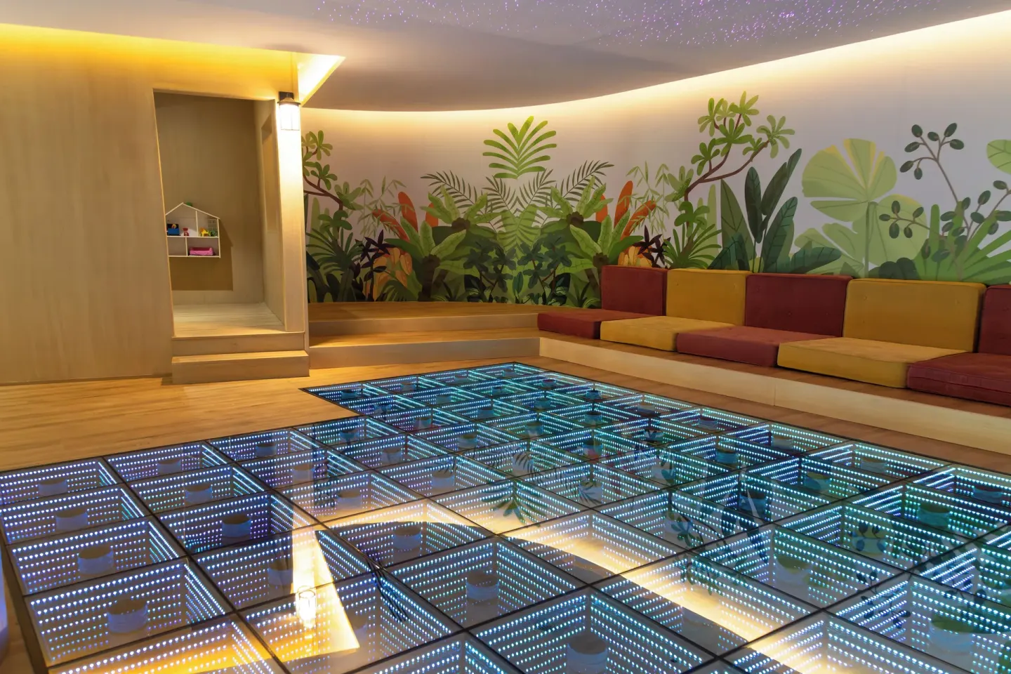 Children's lounge at Grand Velas Riviera Maya with a lighted glass floor and colorful bench seating.