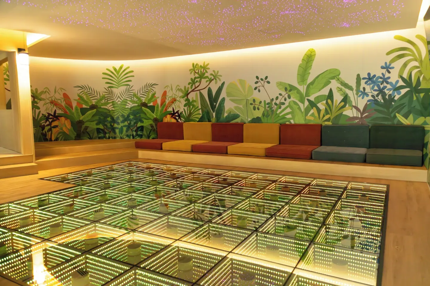 Colorful kids' lounge at Grand Velas Riviera Maya with a glowing floor and tropical mural.