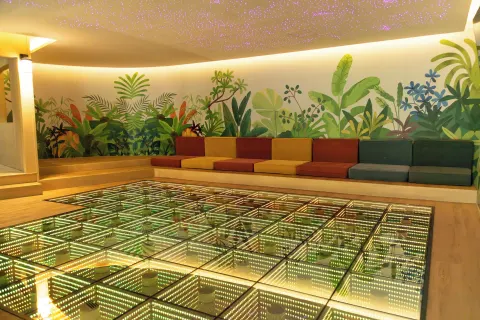 Colorful kids' lounge at Grand Velas Riviera Maya with a glowing floor and tropical mural.