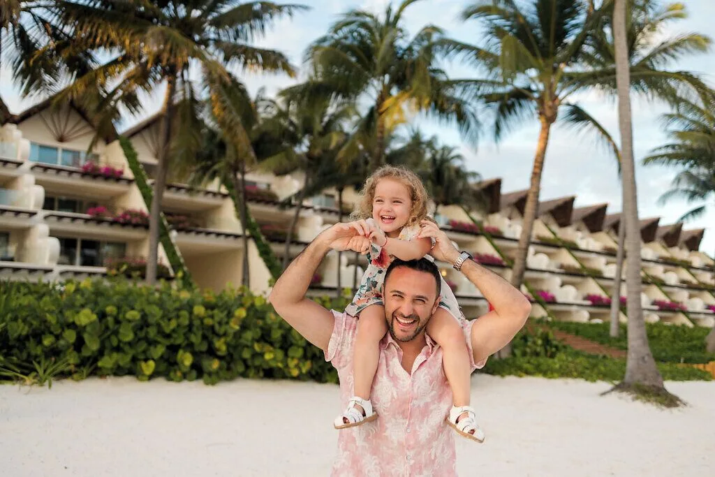Father carrying a child on the beach at Grand Velas Riviera Maya.