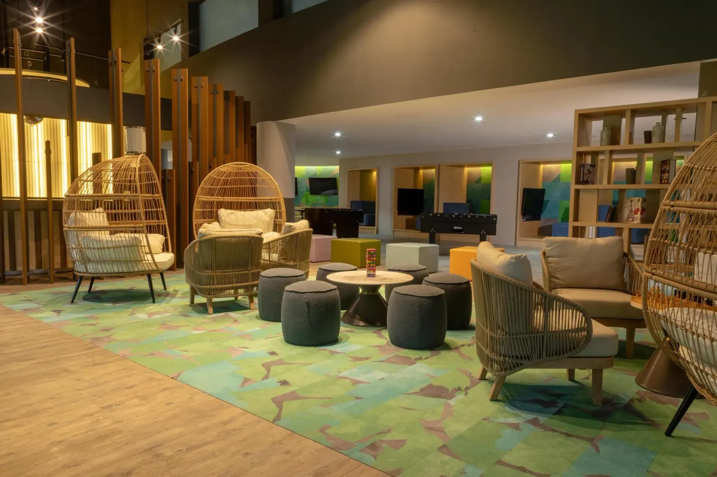 Family lounge with wicker chairs, games and TVs at Grand Velas Riviera Maya.