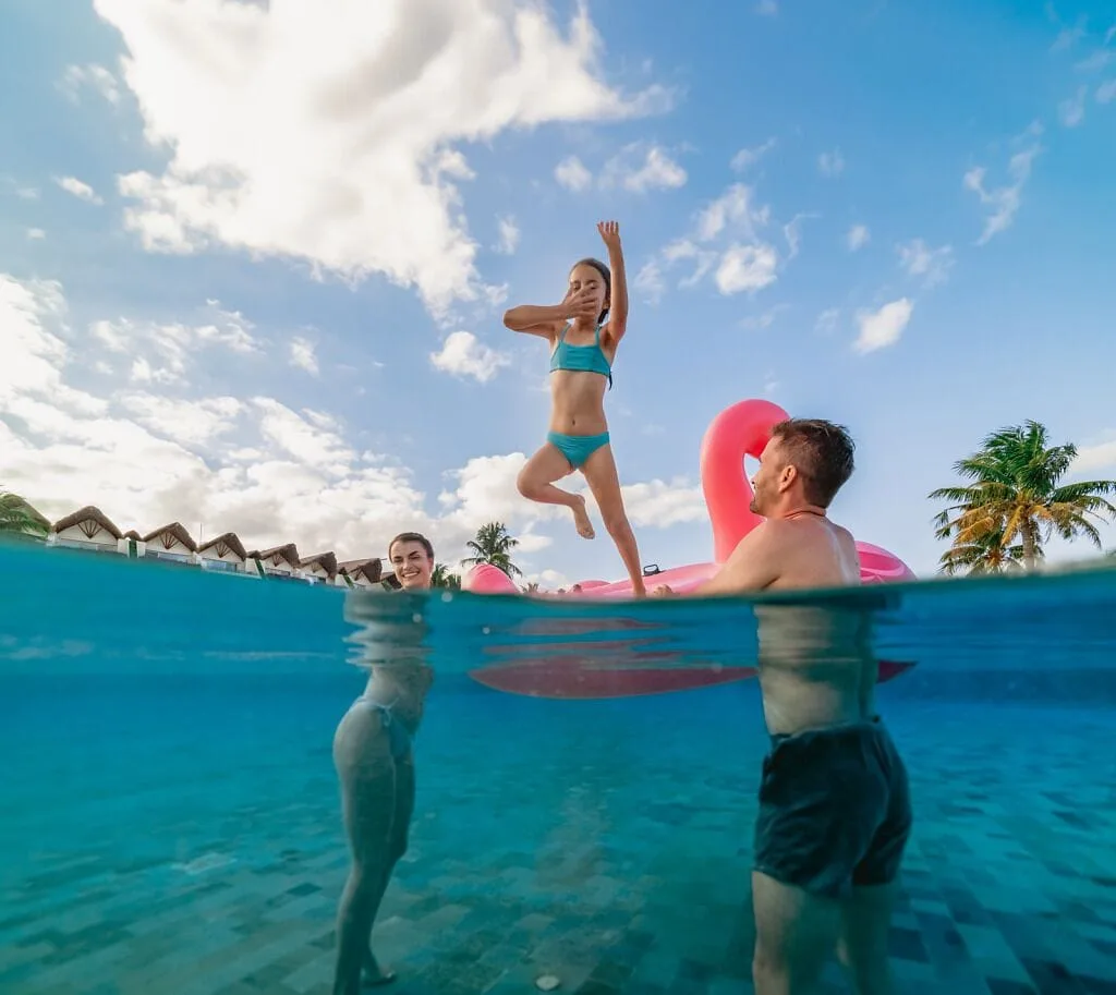 Family plays in the pool with a pink float at Grand Velas Riviera Maya.