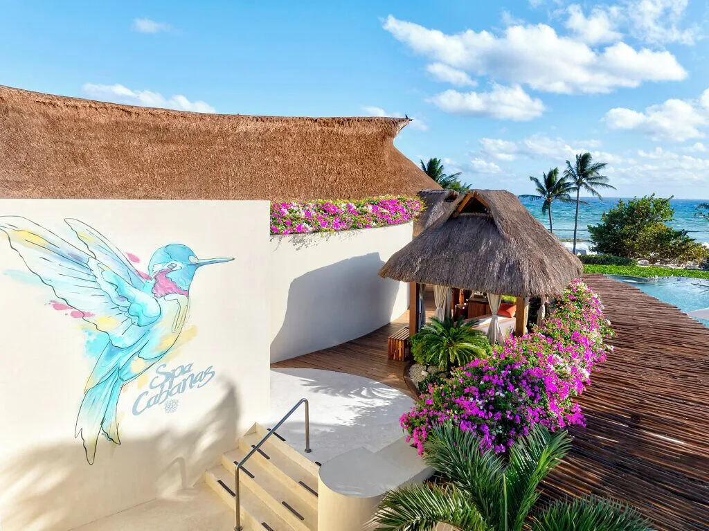 Spa cabanas with thatched roofs and ocean beyond at Grand Velas Riviera Maya.